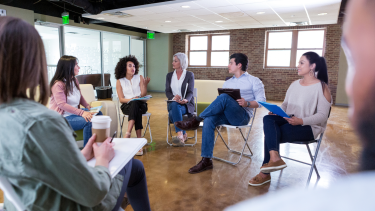 PAC meeting adults sitting in a circle on chairs talking