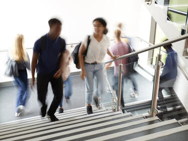 Motion Blur Shot Of High School Students Walking On Stairs Between Lessons In Busy College Building
