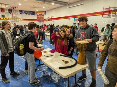 Gym filled with students who are checking out information tables about clubs at the school